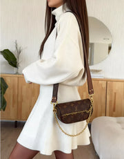 White turtleneck sweater and flared skirt set with a brown monogram crossbody bag.