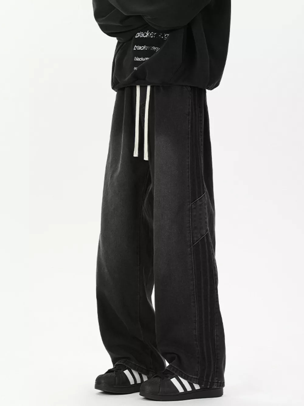 Black relaxed fit wide-leg jeans with drawstring and striped detail.