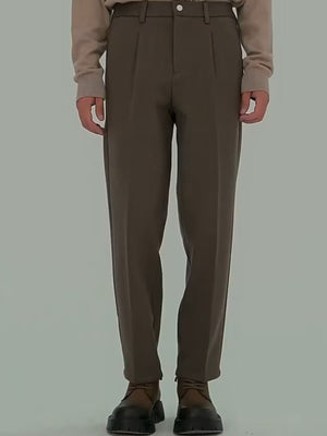 Men's brown pleated trousers with a relaxed fit and visible pockets.