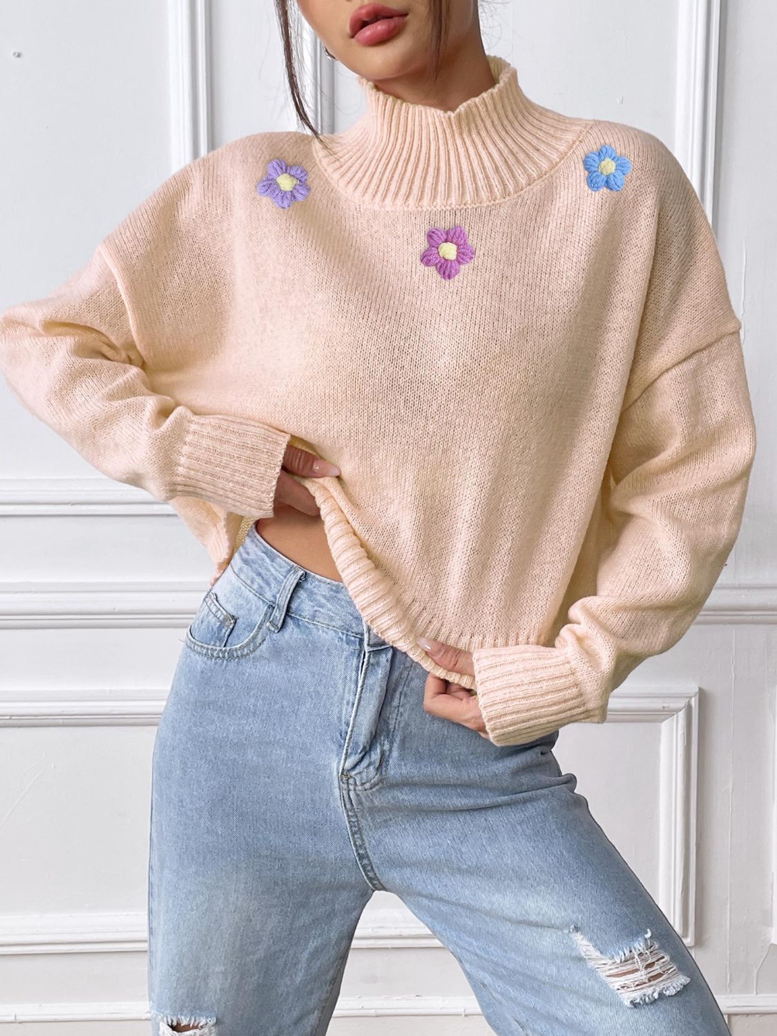 Blush pink cropped turtleneck knit sweater with embroidered floral details.