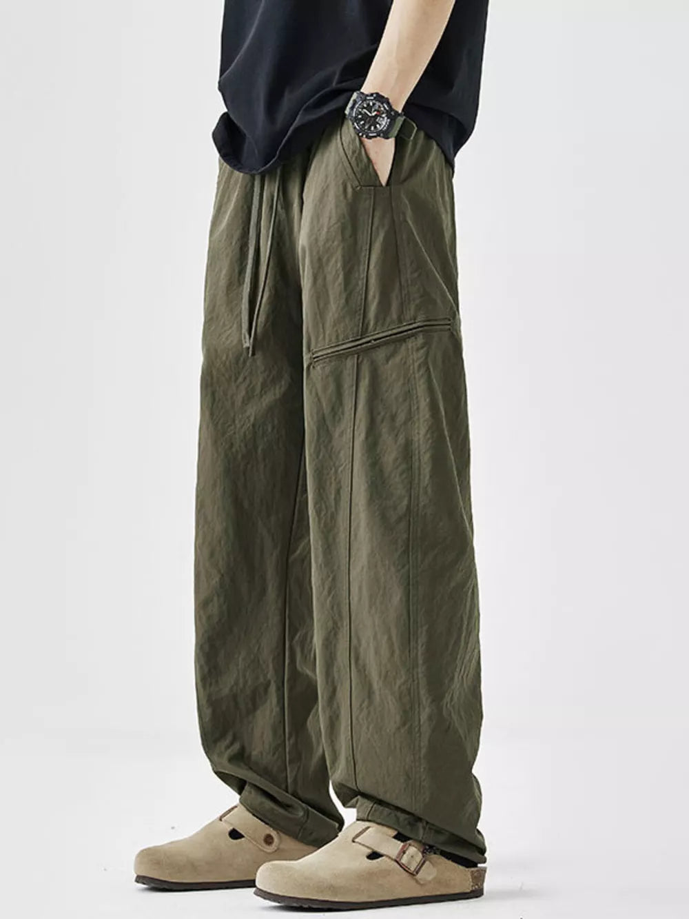 Olive green wide-leg sweatpants with drawstring and zippered pocket detail.
