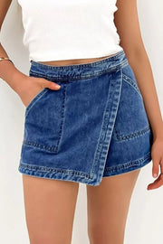 Denim wrap skort in medium wash with patch pockets and asymmetrical hem.