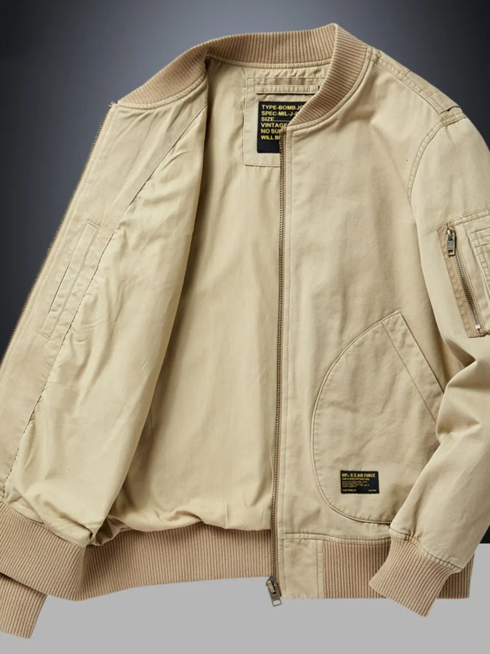 Khaki bomber jacket with patch detail, zip pockets, and ribbed cuffs.