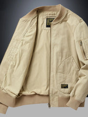 Khaki bomber jacket with patch detail, zip pockets, and ribbed cuffs.
