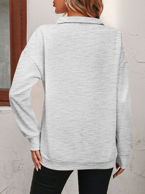 Light gray quarter-zip relaxed fit sweatshirt with long sleeves and a collared neckline.