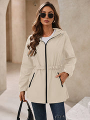 Tan hooded windbreaker jacket with ruffled waistline and black zipper details.