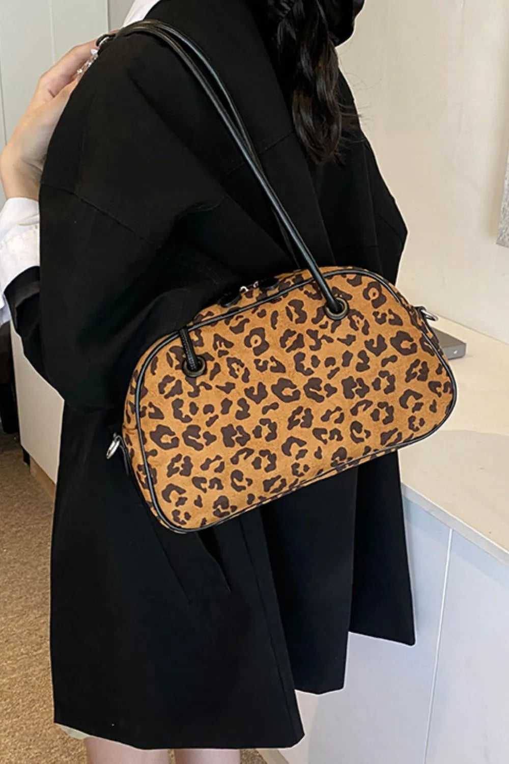 Leopard print barrel bag in caramel with black trim and straps.