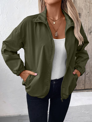 Army green nylon bomber jacket with drawstring hem and zip front, styled with a white tank top.