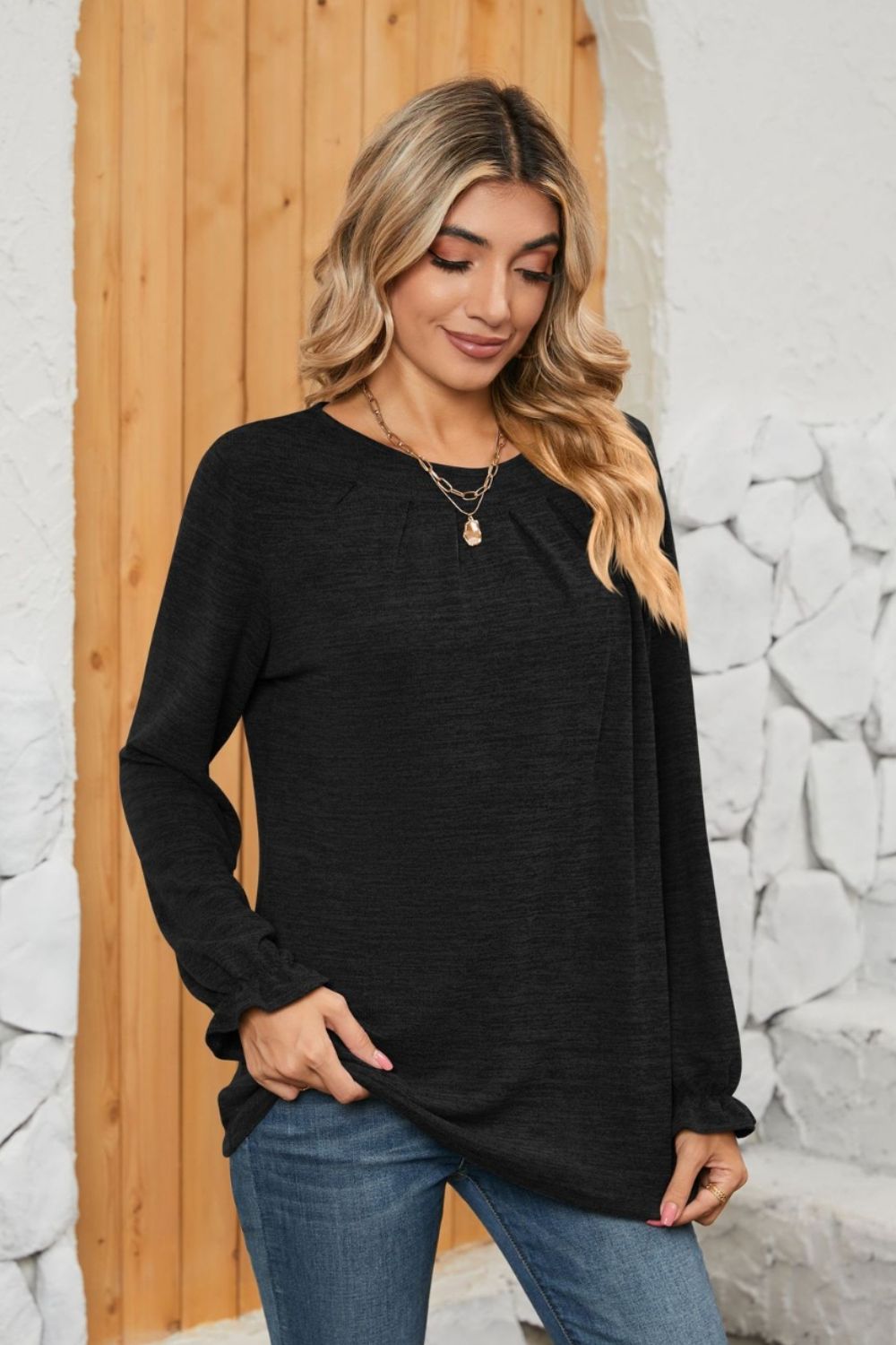Black knit top with pleated yoke and ruffled cuffs, crew neck, long sleeves.