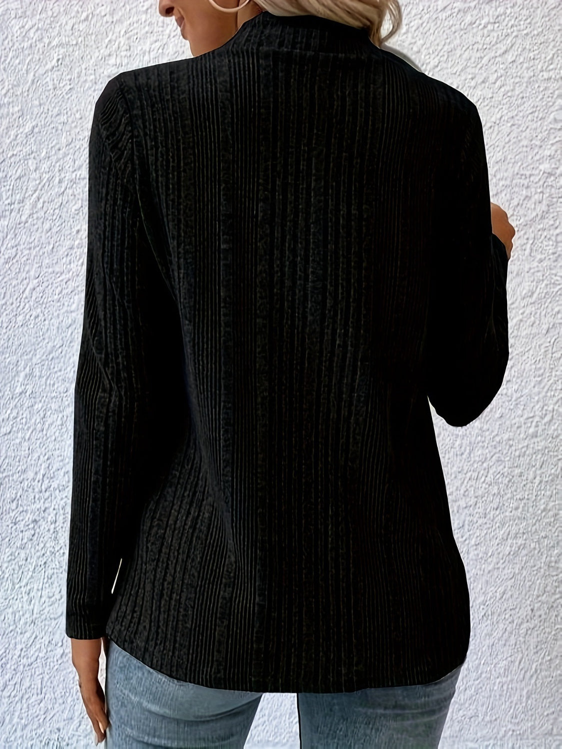 Black ribbed knit cardigan with long sleeves and a draped waterfall front, styled with jeans.