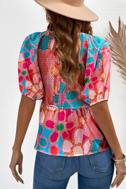 Smocked bodice peplum top with puff sleeves in a vibrant floral print.