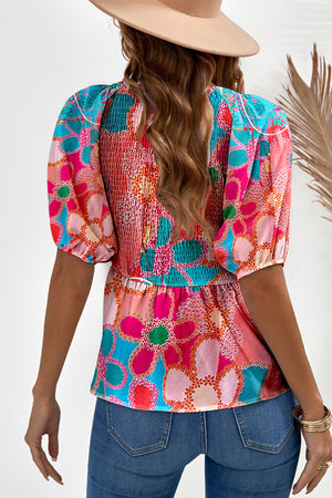 Smocked bodice peplum top with puff sleeves in a vibrant floral print.