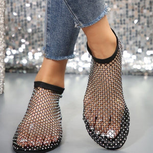 Black fishnet ankle socks with rhinestones, paired with jeans.