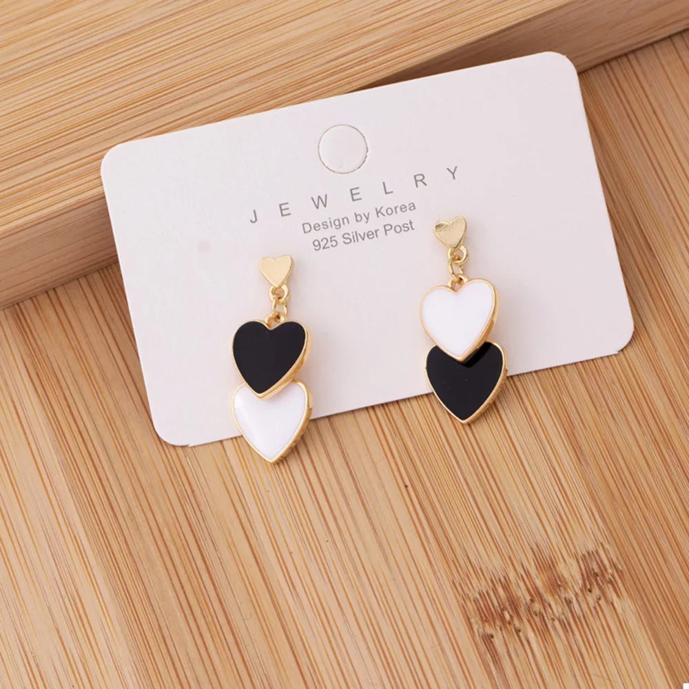 Charming double heart enamel earrings in black and white with gold accents.