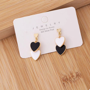 Charming double heart enamel earrings in black and white with gold accents.