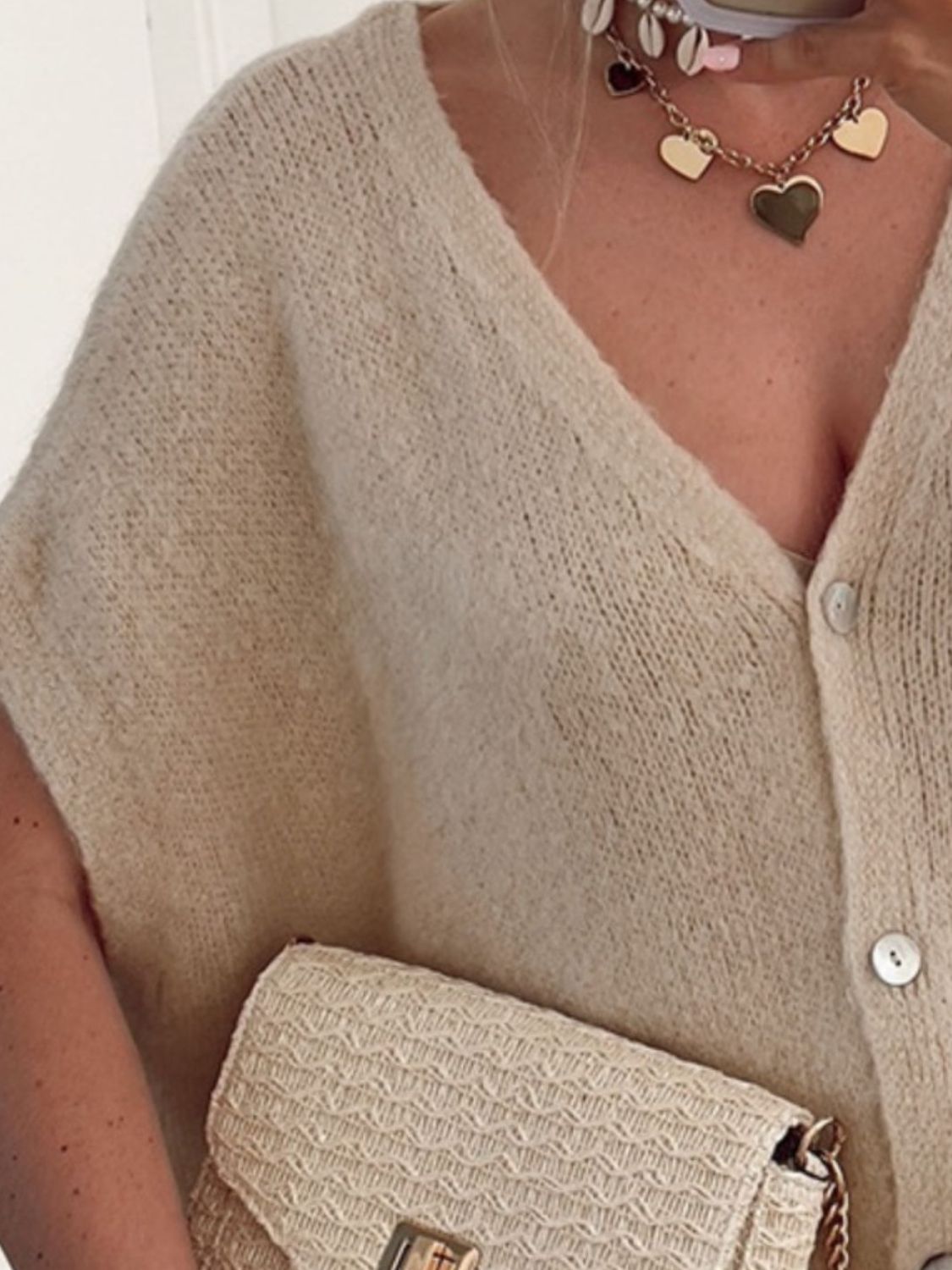 Khaki cap sleeve mohair blend cardigan with V-neck and buttons, styled with a straw clutch.