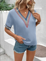 Light blue v-neck blouse with colorful embroidered trim on neckline and sleeves.