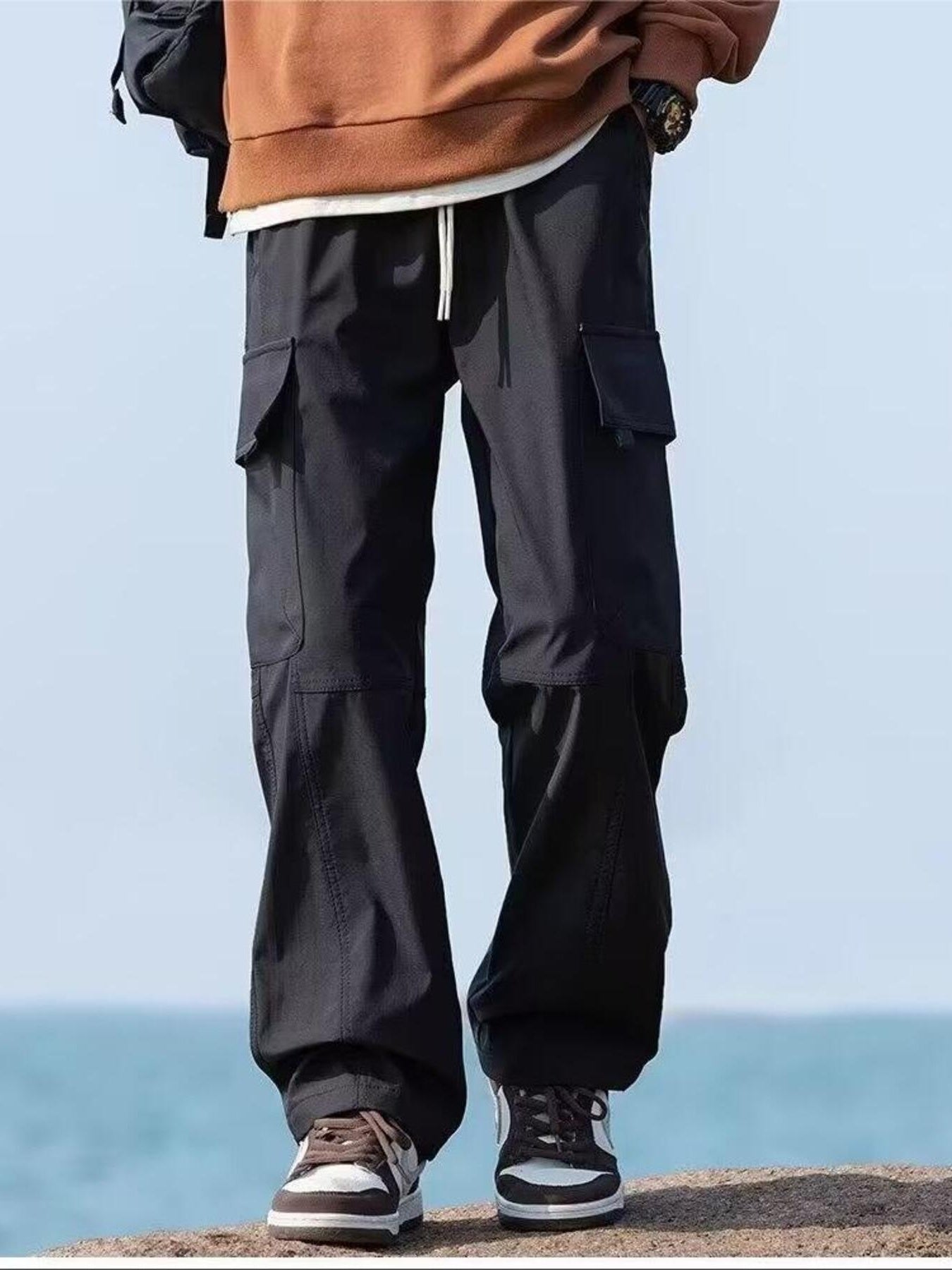 Black relaxed fit cargo pants with flap pockets and drawstring waist.