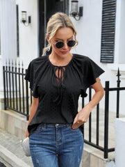 Black perforated tie-neck blouse with flutter sleeves and a diamond pattern.
