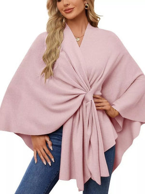 Pink knit cape top with tie-front detail and draped elegance.
