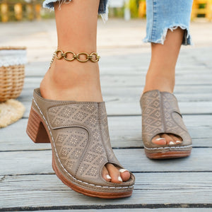 Tan peep-toe mules with laser-cut diamond pattern and block heel.
