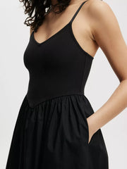 Black midi dress with V-neck, ribbed bodice, and full skirt with pockets.