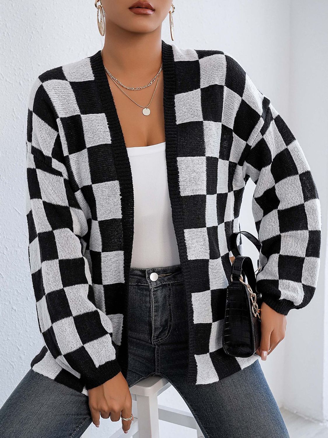 Checkerboard knit cardigan in black and white with balloon sleeves and an open front.