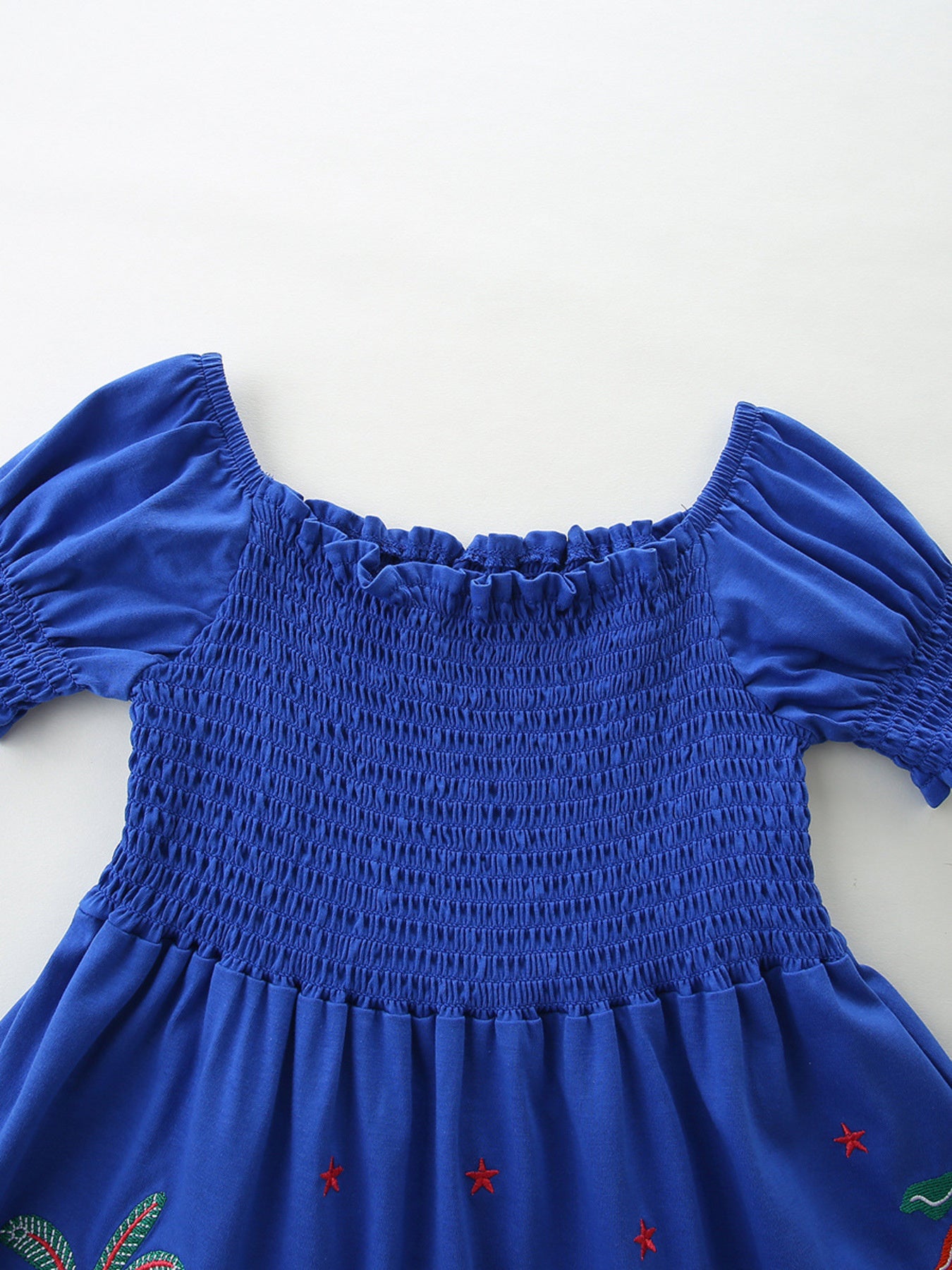 Blue cotton baby dress with smocked bodice, puff sleeves, and jungle print detail.