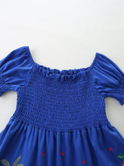 Blue cotton baby dress with smocked bodice, puff sleeves, and jungle print detail.