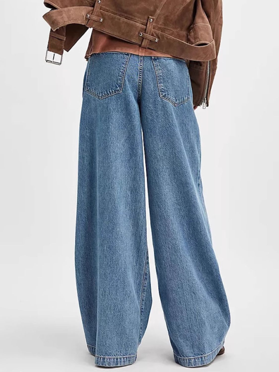 Pleated wide-leg denim trousers in dusty blue with a buttoned closure and back pockets.
