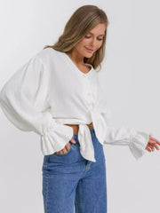 White textured puff sleeve blouse with tie front and ruffled cuffs.