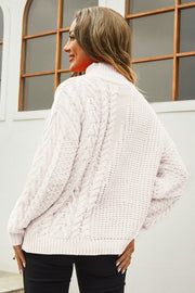 Beige cable-knit turtleneck sweater with voluminous silhouette and textured details.