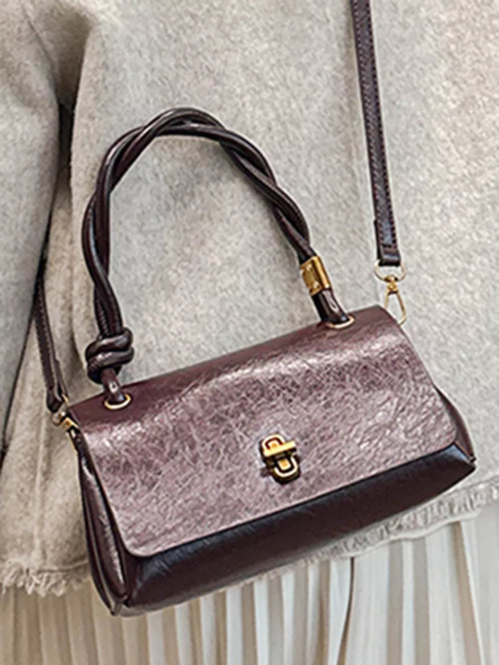 Chic brown crossbody bag with twisted handle and gold clasp closure.