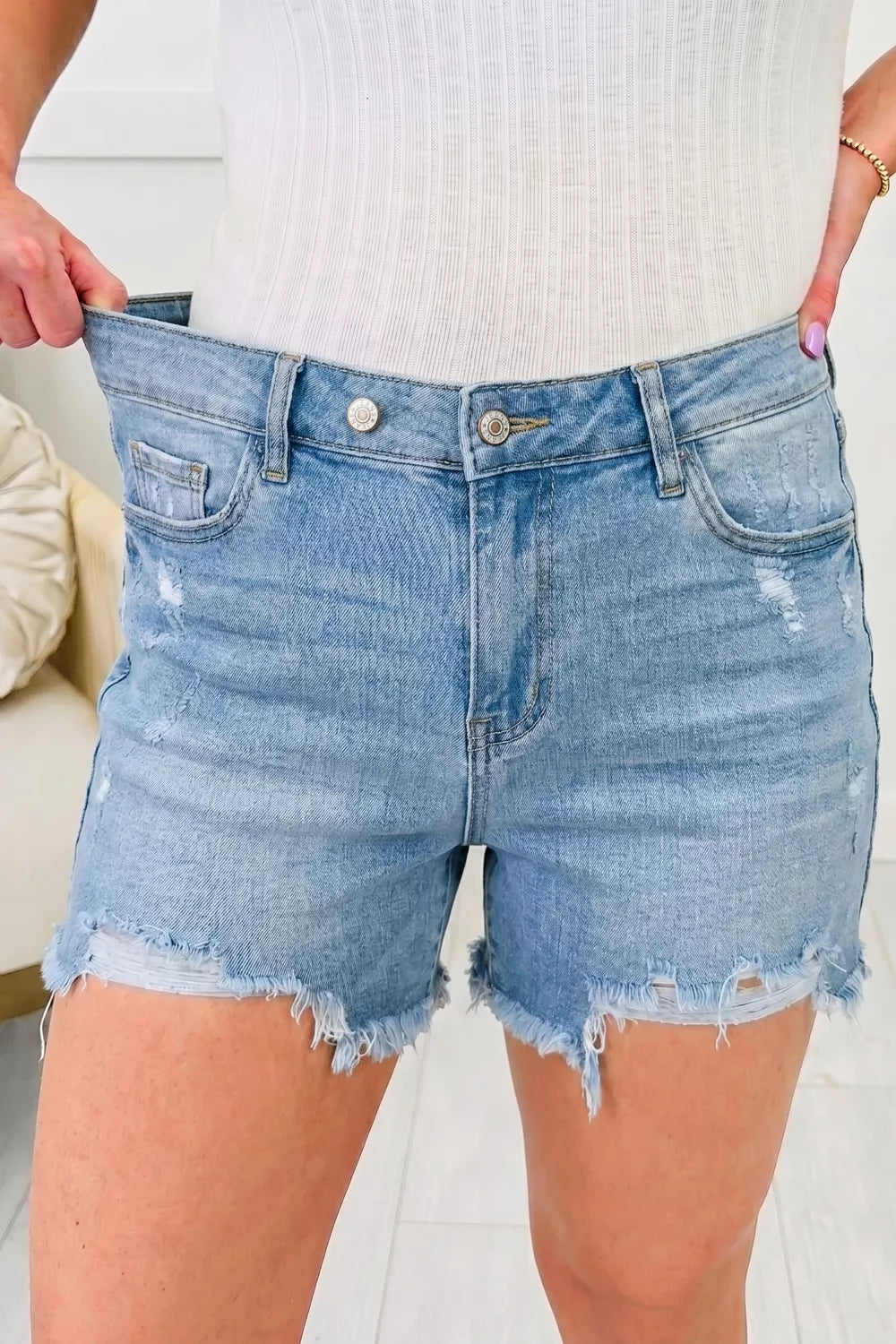 Light wash denim shorts with raw hem and distressed details