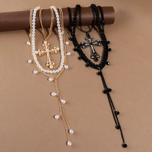 Gold and black pearl cross pendant necklaces with layered chains and dangling pearls.