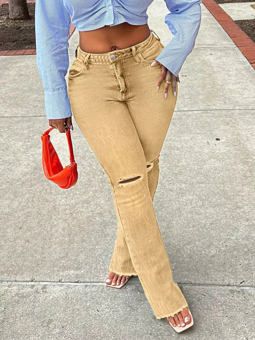 Distressed flare jeans in yellow denim with raw hem and knee rip.