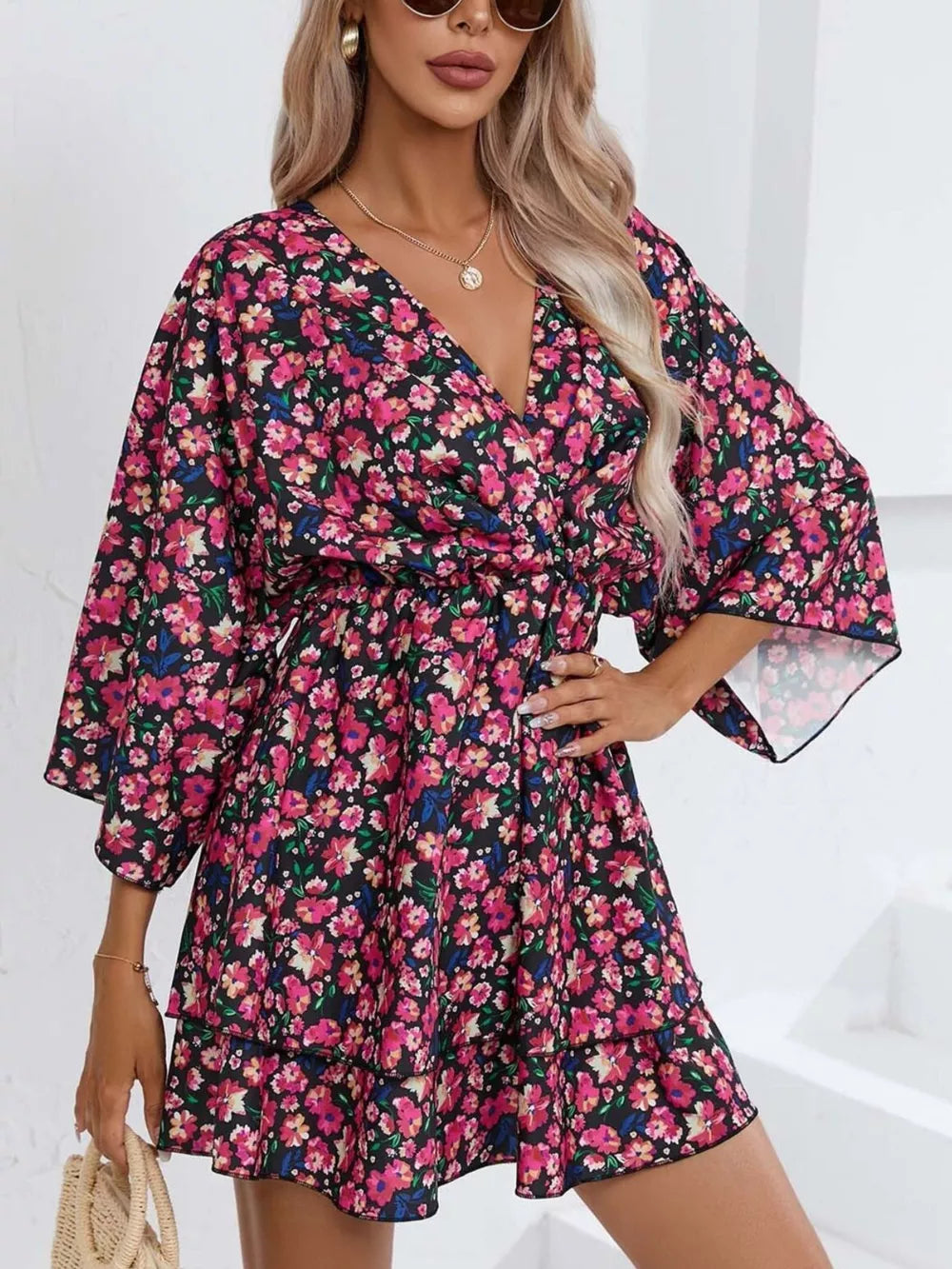 Floral ruffle hem mini dress in black with pink and blue flowers, featuring a V-neck and bell sleeves.