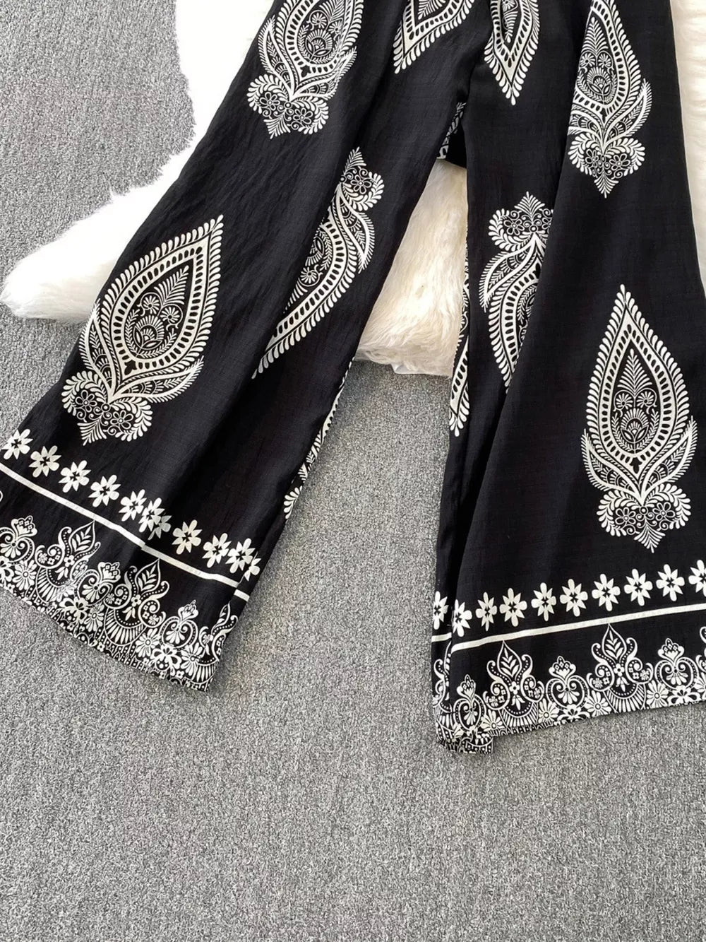Black wide leg romper with white paisley and floral print details.