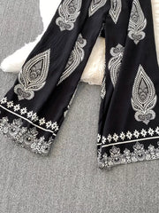 Black wide leg romper with white paisley and floral print details.