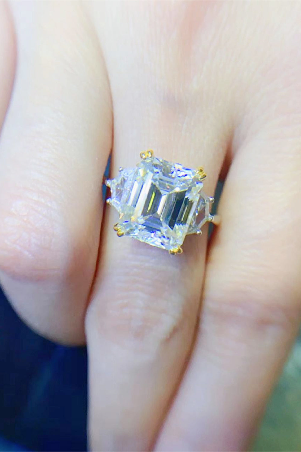 Emerald cut trilogy ring in silver with gold accents and clear stones.