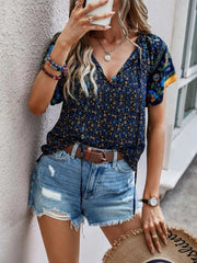 Dark blue floral print blouse with flutter sleeves and tie neck, paired with distressed denim shorts.