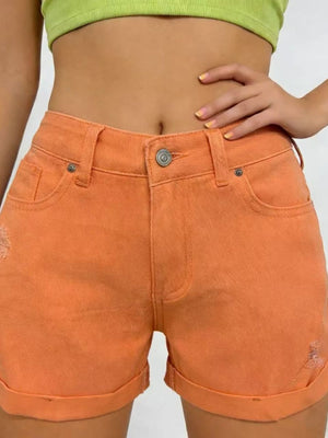 Orange-red cuffed denim shorts with distressed details and high waist.