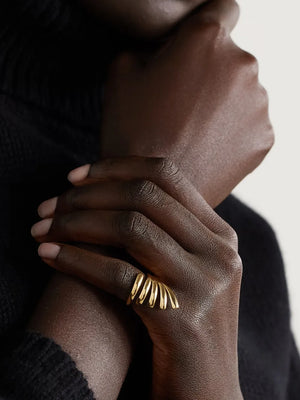 Gold-plated ribbed ring with a sculptural design on a woman's finger.
