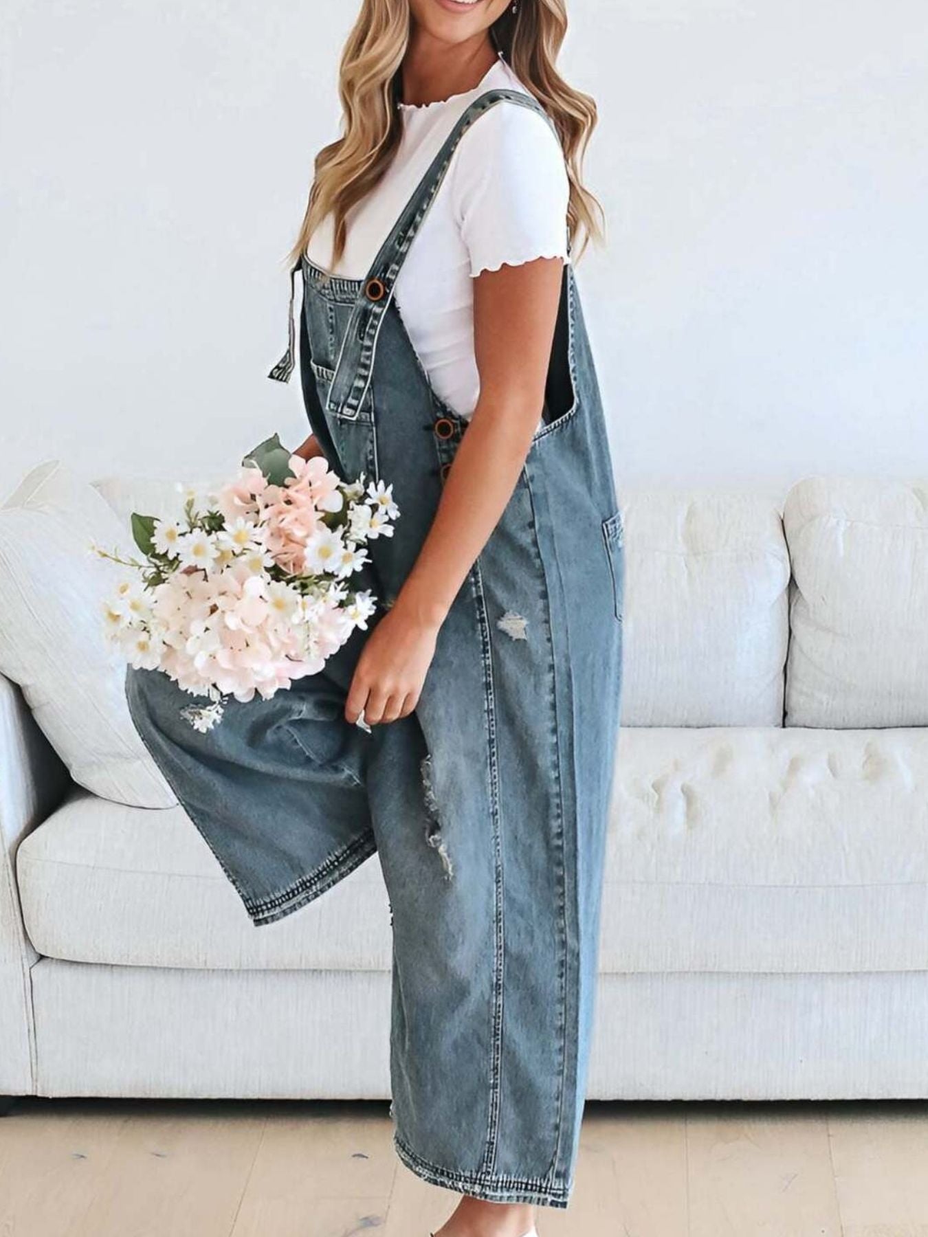 Ripped relaxed fit denim overalls in light blue with adjustable straps and distressed details.