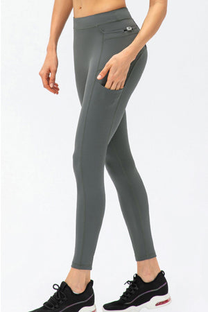 Dark gray athletic leggings with utility pockets and a zippered back pocket.