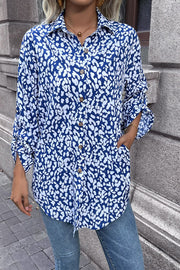 Sky blue oversized shirt with abstract spot print, buttoned front, and rolled sleeves.
