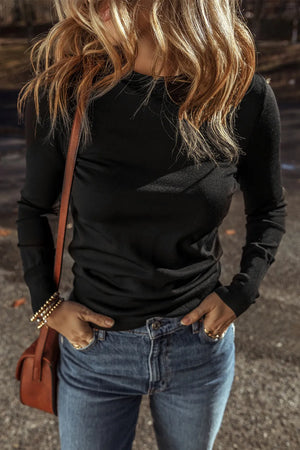 Black long sleeve crewneck top with sculpted detail, styled with jeans.