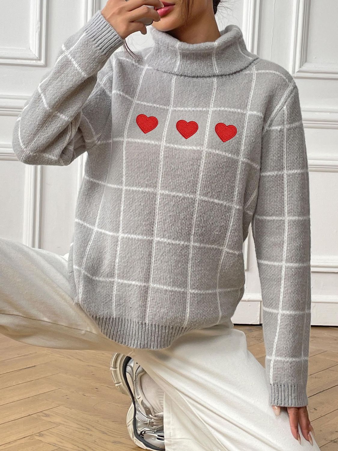 Light gray grid turtleneck sweater with red heart appliqués.