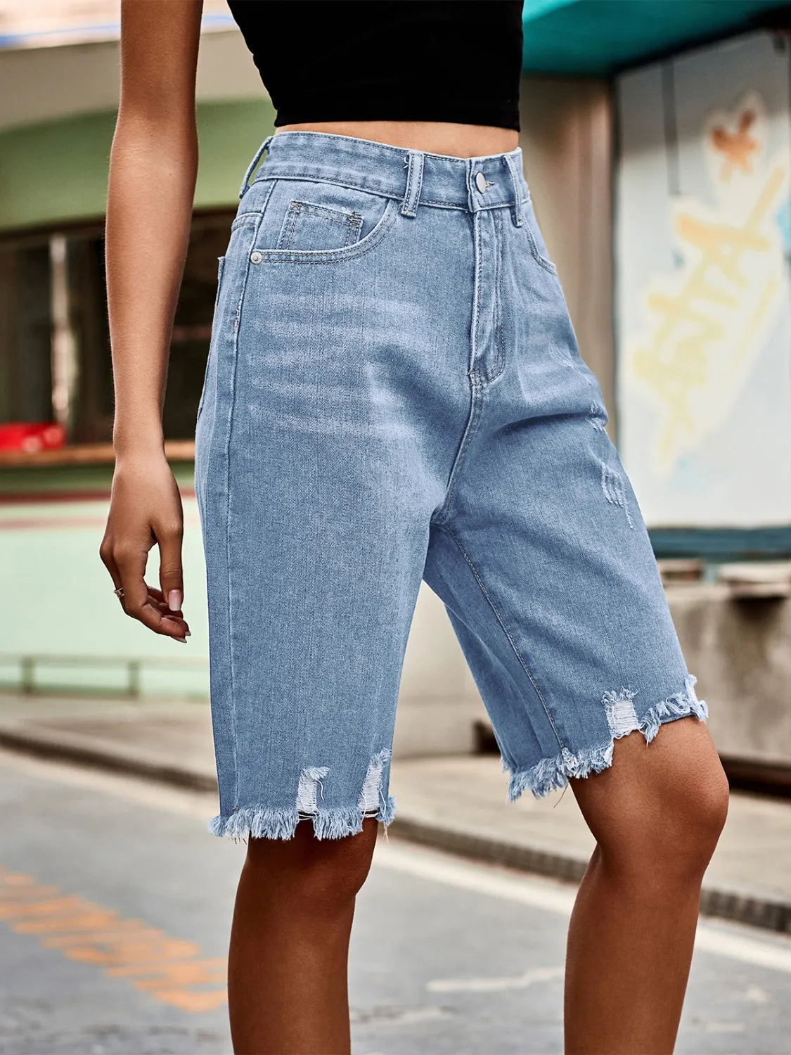 Light blue denim knee-length shorts with distressed details and frayed hem