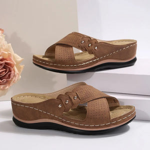 Camel perforated cross-strap comfort sandals with white stitching detail.